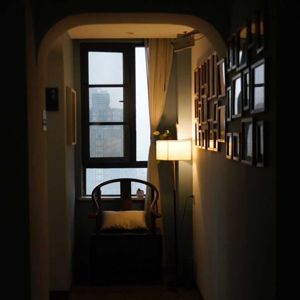 Coin d'un appartement faiblement éclairé avec chaise et lampe près d'une fenêtre